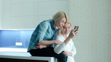 İki kadın fotoğrafları Smartphone izlerken