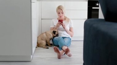 Kadın evde beslenen hayvan köpek mutfak smartphone kullanırken