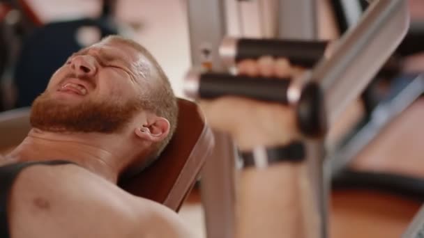 Jonge witte bodybuilder borst druk op in de simulator maken — Stockvideo