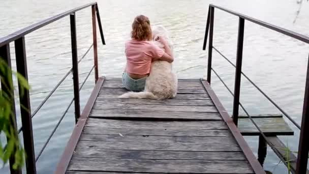 Woman sitting n the pontoon with her labrador — Stock Video