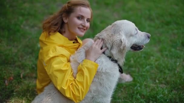 Mulher de capa amarela sentada com um cachorro . — Vídeo de Stock