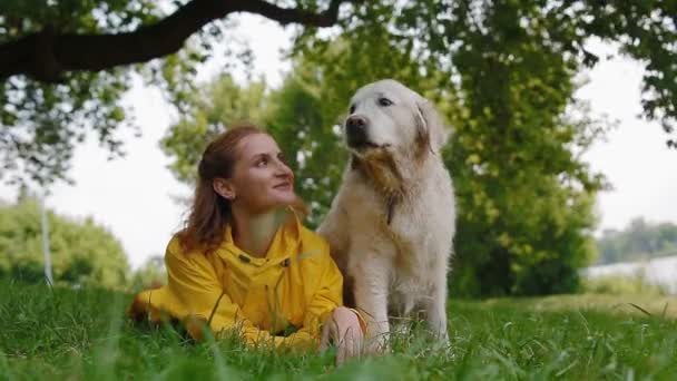 Kvinna i gul regnrock sitter med en hund. — Stockvideo