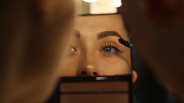 Frau trägt Wimperntusche auf und schaut in den Spiegel — Stockvideo