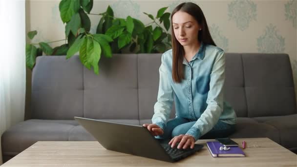 Senhora de cabelos longos senta-se à mesa de madeira com laptop preto — Vídeo de Stock