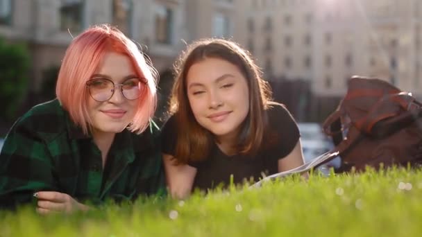 Две студентки на траве с книгой — стоковое видео