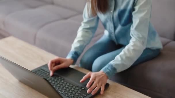 Wütende Brünette tippt auf Laptop und schließt auf Sofa sitzend — Stockvideo