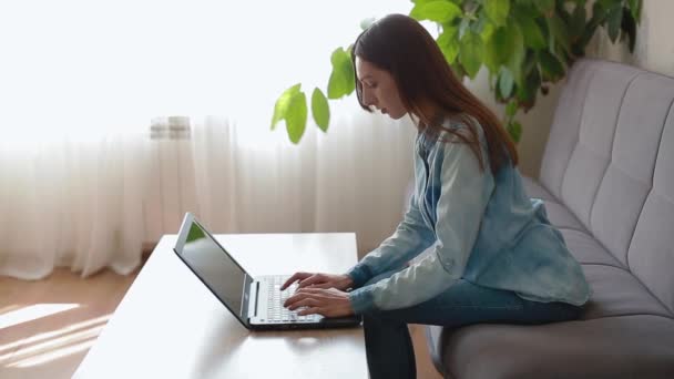 Lang haar dame zit aan houten tafel met zwarte laptop — Stockvideo