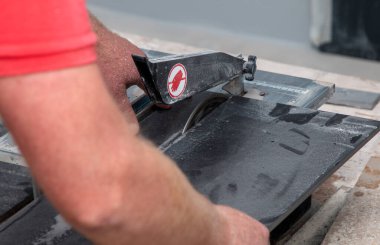 Bir adam özel bir makinenin fayanslarını metal bir çemberle keser.