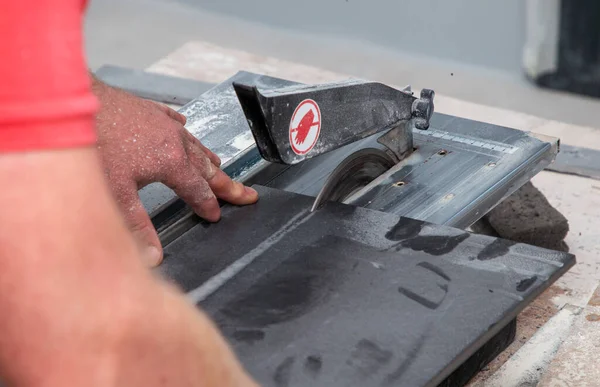 Seorang pria memotong ubin pada mesin khusus dengan lingkaran logam — Stok Foto