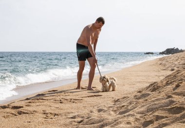 Bir adam plajda koşuyor sağlık maskesi ve bir köpekle