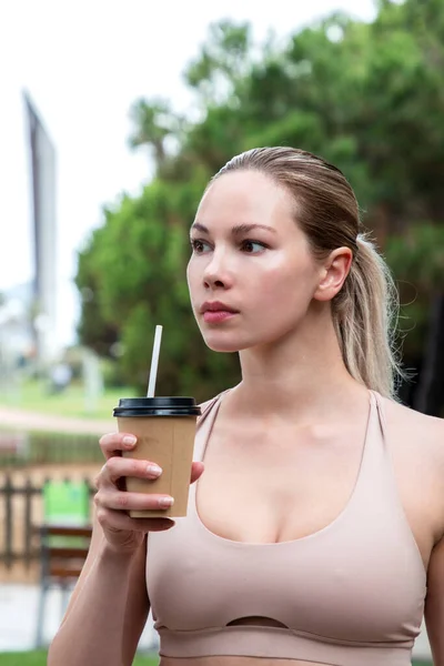 Güzel kız doğada bir karton bardaktan su içiyor.