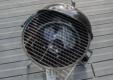 Terasta izole edilmiş siyah bir barbekü ızgarası.