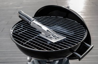 Terasta izole edilmiş siyah bir barbekü ızgarası.