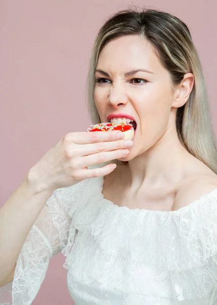 Piękna dziewczyna bawiąca się pączkami na różowym tle. Dieta, koncepcja diety. Niezdrowe jedzenie, utrata masy ciała — Zdjęcie stockowe