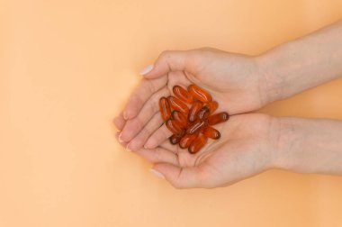 Turuncu arka planda vitamin demet ile güzel eller