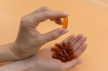 Turuncu arka planda vitamin demet ile güzel eller