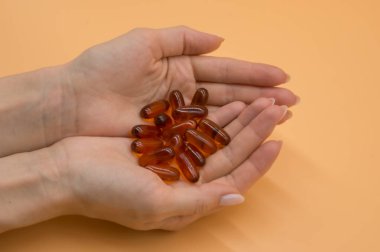 Turuncu arka planda vitamin demet ile güzel eller