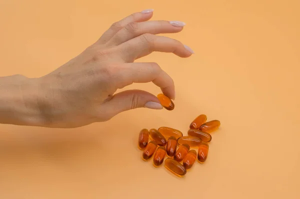 오렌지 배경에 비타민의 무리와 아름다운 손 — 스톡 사진