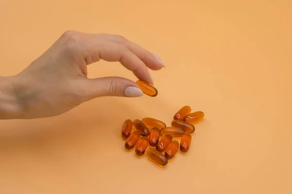 오렌지 배경에 비타민의 무리와 아름다운 손 — 스톡 사진