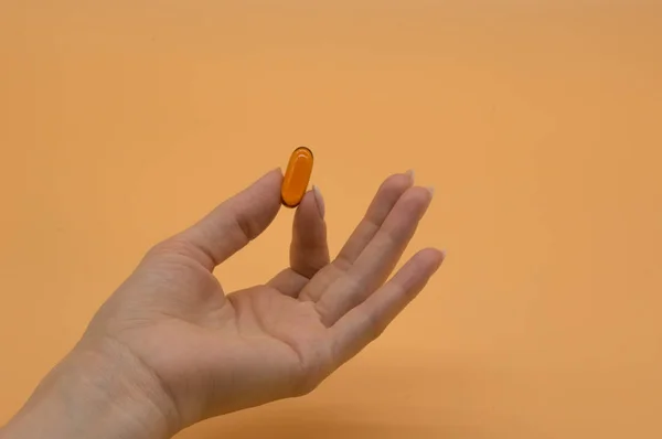 Belas mãos com molho de vitaminas no fundo laranja — Fotografia de Stock