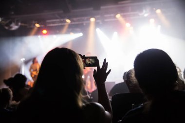 Kalabalık konser ve bulanık sahne ışıkları. Smartphone ile bir konser sırasında fotoğraf çekmek yakın çekim .
