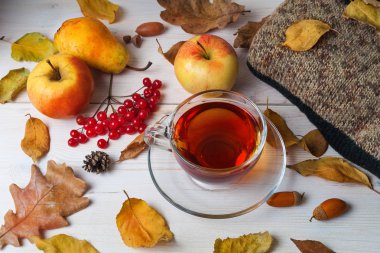 Ahşap bir arka plan üzerinde çay, sonbahar yaprakları ve meyve fincan.