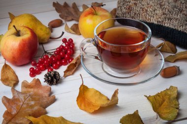 Ahşap bir arka plan üzerinde çay, sonbahar yaprakları ve meyve fincan.