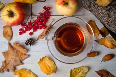 Ahşap bir arka plan üzerinde çay, sonbahar yaprakları ve meyve fincan.