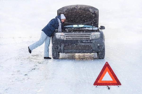 Woman looking on the broken car looking at the motor. Around winter and snow field. — Stock Photo, Image