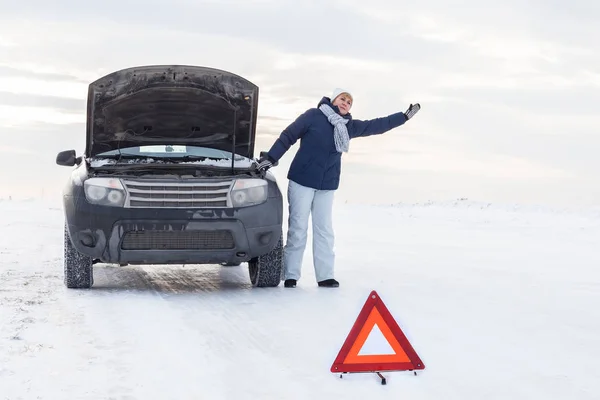 Woman looking on the broken car looking at the motor. Around winter and snow field. — Stock Photo, Image