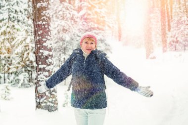 Kış ormanında yürüyen bir kadın. Orta yaşlı bir kadın parkta donuyor..