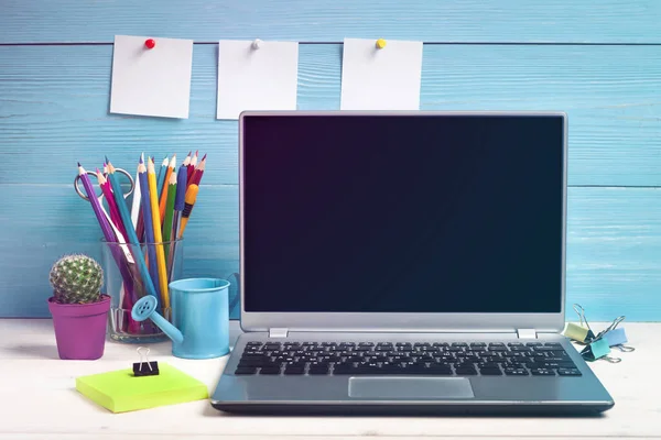 Dizüstü bilgisayar ve ofis malzemeleri tasarımcının masasında.