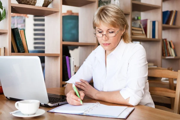 Взрослая женщина, работающая на ноутбуке в офисе — стоковое фото