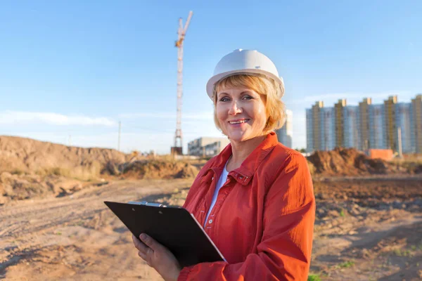 İnşaat alanındaki orta yaşlı bir kadın yapılan işi inceliyor.