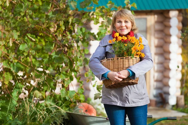 Sonbahar bahçesinde bir kadın çöpleri toplar ve temizler..