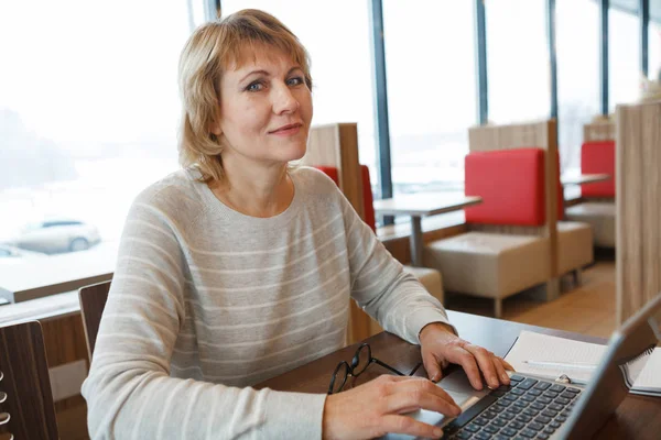 Uma mulher num café a trabalhar num computador à janela . — Fotografia de Stock
