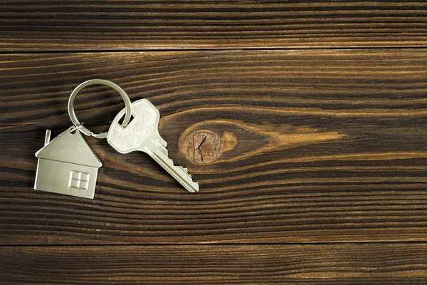 Klucze do domu leżą na ciemnym drewnianym tle. Koncepcja kupna mieszkania. — Zdjęcie stockowe