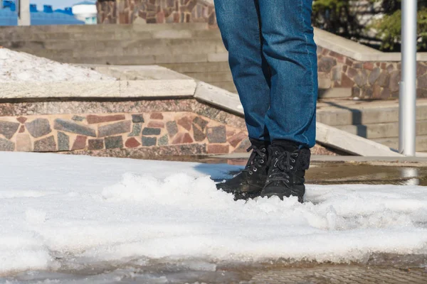 A woman in shoes is on the spring road through puddles and snow — Stock Photo, Image