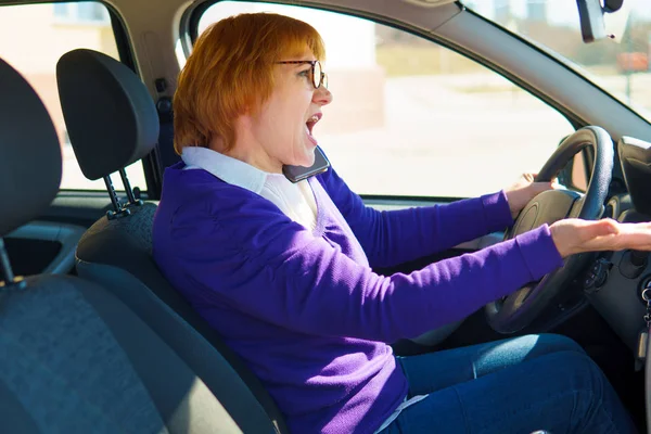 En kvinna i blå jacka kör en bil genom staden. — Stockfoto