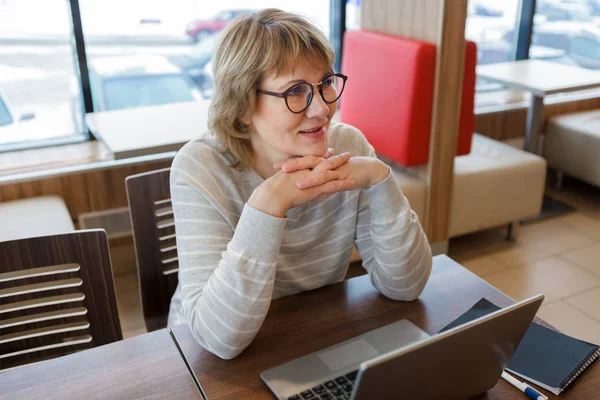 Uma mulher trabalha em um escritório e café com um laptop, ela tem um trabalho remoto — Fotografia de Stock