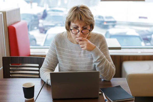 En kvinna arbetar på ett kontor och café med en laptop, hon har ett avlägset jobb — Stockfoto