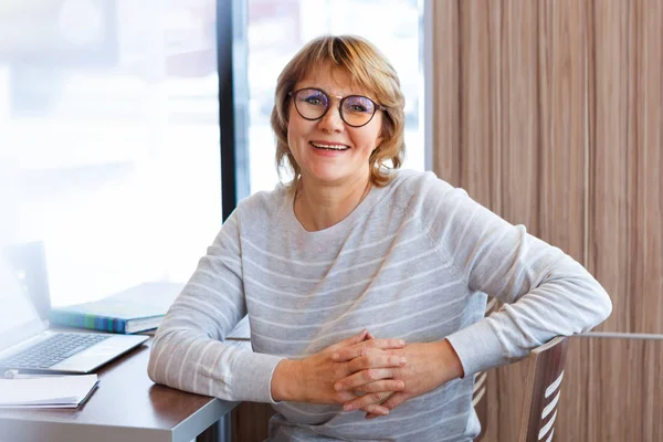 En kvinna arbetar på ett kontor och café med en laptop, hon har ett avlägset jobb — Stockfoto