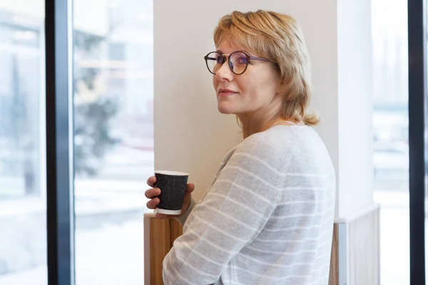 Uma mulher trabalha em um escritório e café com um laptop, ela tem um trabalho remoto — Fotografia de Stock