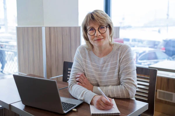 Mulher de meia-idade negócios no local de trabalho no café, escritório, ela está trabalhando em seu laptop . — Fotografia de Stock