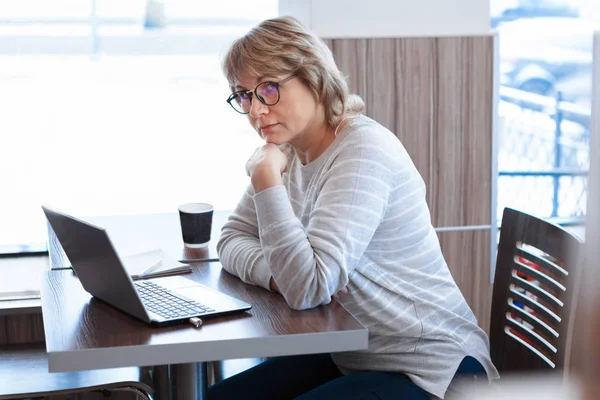 Женщина среднего возраста бизнес на рабочем месте в кафе, офисе, она работает на своем ноутбуке . — стоковое фото