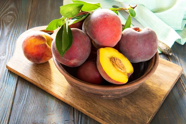 Sweet ripe juicy peaches with green leaves on a wooden background