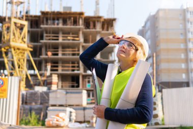 İnşaat alanındaki bir kadın inşaatçı tuğladan yapılmış bir evi inceliyor.