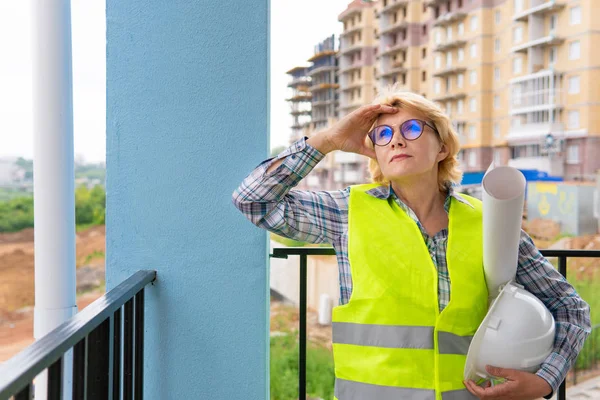 Una mujer Constructora en un sitio de construcción inspecciona una casa hecha de ladrillo — Foto de Stock