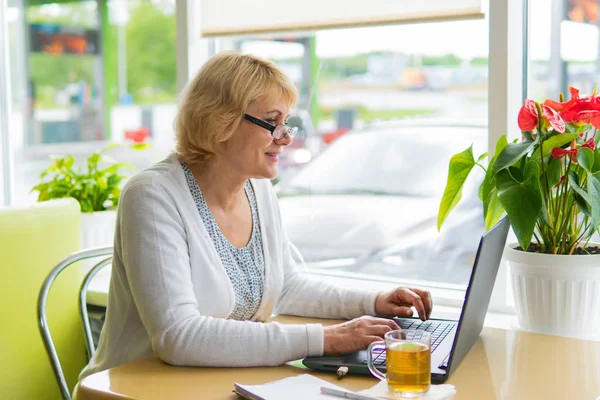 Mulher com um laptop trabalha em um café no escritório, ela é freelancer . — Fotografia de Stock