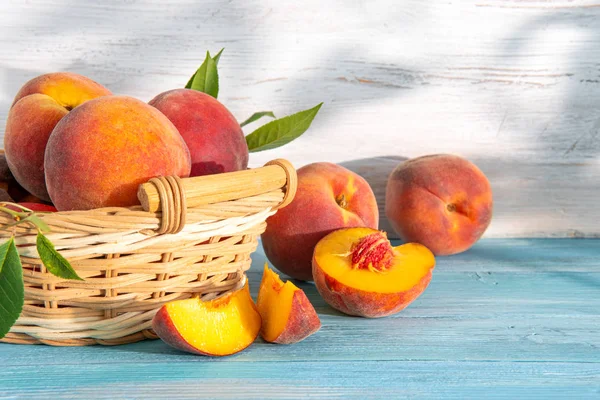 Sweet ripe juicy peaches with green leaves on a wooden background